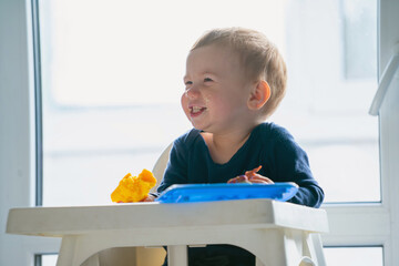 Happy toddler laughing during breakfast, concept of joyful childhood