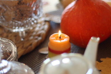 Lit candles, cookies, chocolate, nuts, tea, wine, pumpkins, books, reading glasses and autumn leaves on the table. Autumnal hygge at home. Selective focus.