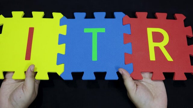hands holding foam puzzle pieces spelling the acronym itr on black