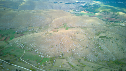 Drone aerial view of Monte Calascio, Abruzzo, featuring the medieval Rocca fortress and spectacular surrounding mountain landscapes