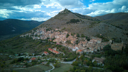 Drone aerial view of Monte Calascio, Abruzzo, featuring the medieval Rocca fortress and spectacular surrounding mountain landscapes