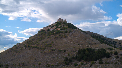 Drone aerial view of Monte Calascio, Abruzzo, featuring the medieval Rocca fortress and spectacular surrounding mountain landscapes