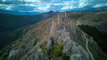 Drone aerial view of Monte Calascio, Abruzzo, featuring the medieval Rocca fortress and spectacular surrounding mountain landscapes