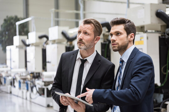 Businessmen discussing in production facility with machinery