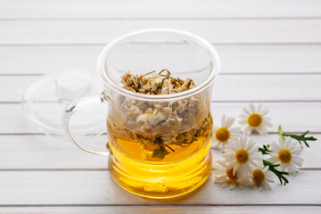 Cup of herbal chamomile tea and daisy flowers.