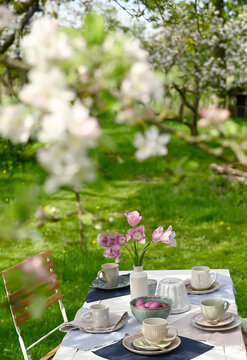 Spring breakfast table with flowers and Easter eggs outdoors in a garden