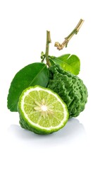 Green citrus fruits, one sliced open, leaves, and stem on white background