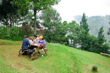 Obraz premium Young Professionals Collaborating on Laptop Outdoors Amidst Lush Green Nature and Misty Mountain