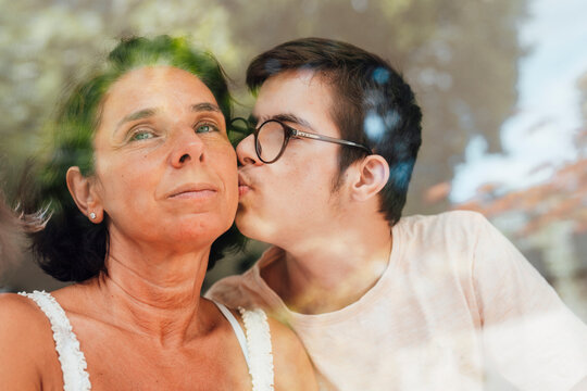 Teenage boy with trisomy 21 kissing mother showing love and trust
