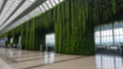 Blurred background of an artificial waterfall located in the middle of the airport with vines in a modern and environmentally friendly airport.