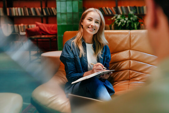 Businesswoman smiling during office meeting and discussion with colleague