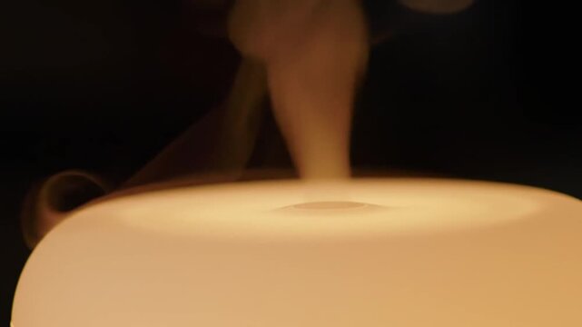 Abstract close up of light diffuser releasing steam against dark background