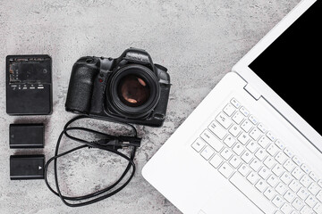 Professional Photographer's Gear Setup With Camera, Batteries, Charger, And Laptop