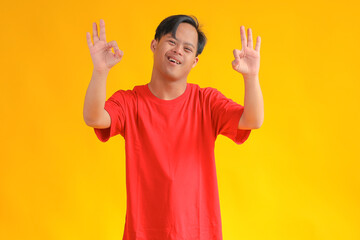 Smiling Young Man Gives Okay Hand Sign, Radiating Positivity Against Yellow Background