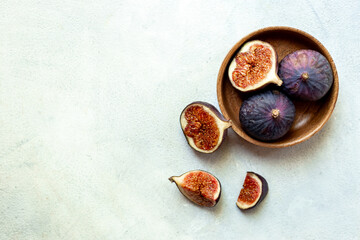 Fresh ripe figs on a wooden bowl top view on a stone background