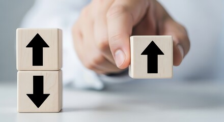 Hand holding wooden block with upward arrow, symbolizing growth and progress, next to stacked blocks with up and down arrows