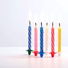 Six burning, colorful spiral candles on a white surface