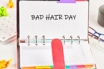 A planner highlights the phrase bad hair day while surrounded by vibrant sticky notes and office supplies, showcasing a lighthearted approach to daily challenges