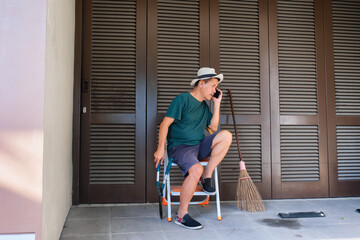 Man sitting on folding ladder answering a phone call during housekeeping