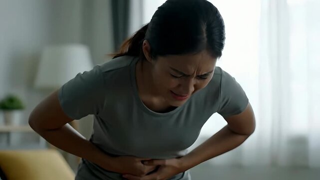 Asian Woman Experiencing Agonizing Stomach Pain at Home