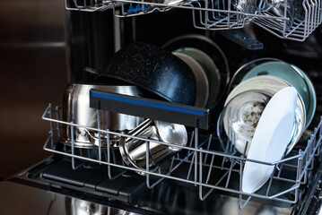 An open dishwasher with clean dishes in the kitchen.