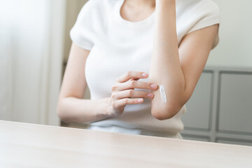 Health skin care, beauty asian young woman, girl hand applying, putting moisturizer on her arm, elbow after shower bath in room at home. Skin body cream moisturizing lotion, routine in morning.