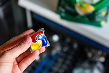 Woman putting detergent capsule into dishwasher.