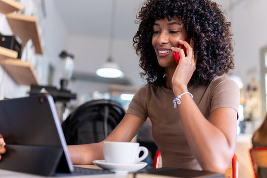 Young woman communicating on phone using tablet in cafe - Powered by Adobe