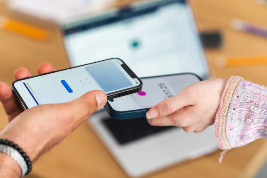 A person uses a mobile device to make a contactless payment, holding it near another device.