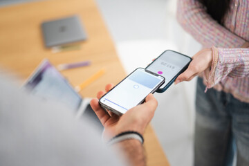 Two people are using their mobile phones to make a contactless payment. One phone displays a payment amount of $17.25.