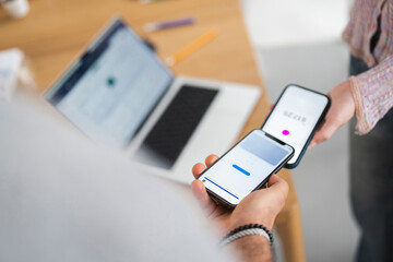 Two people are using their mobile phones to scan each other's digital vaccination passes, demonstrating a contactless verification process.