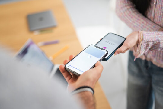 Two people are using their mobile phones to make a contactless payment. One phone displays a payment amount of $17.25.