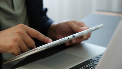 Businessman using digital tablet near laptop in office, focused on screen