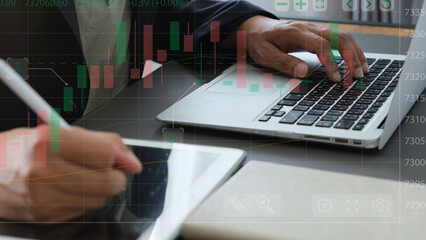 Businessman using laptop and digital tablet for stock market analysis, financial data and candlestick chart overlay showing investment strategy and trading decision process