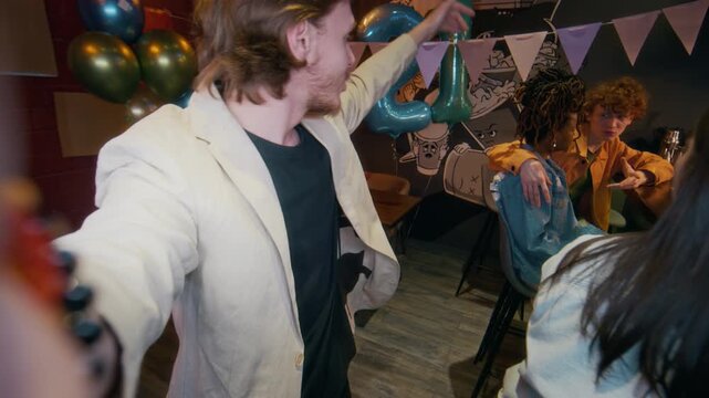 Portrait shot of young adult bearded man talking to camera and recording joyful birthday celebration with friends in bar