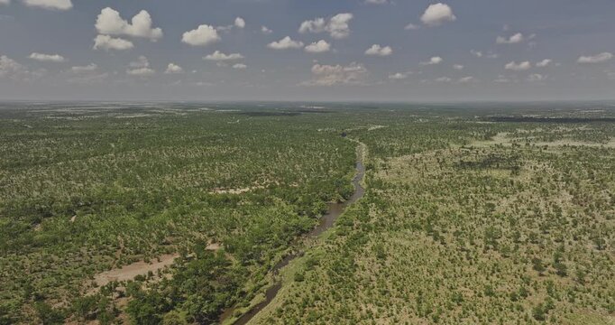 Hwange Park Zimbabwe Aerial v7 rising flyover around Deka river, capturing it winding through a vast, sparsely forested savanna landscape under a cloudy sky - Shot with Mavic 3 Pro Cine - Jan 4th 2024