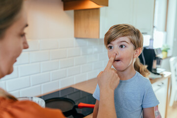 Playful moment of mother touching son s nose in kitchen