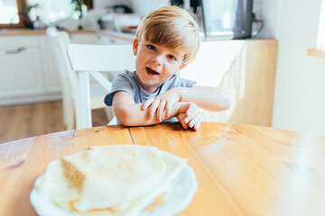 Little boy sitting at kitchen table waiting for pancakes