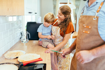 Family cooking pancakes together in bright home kitchen