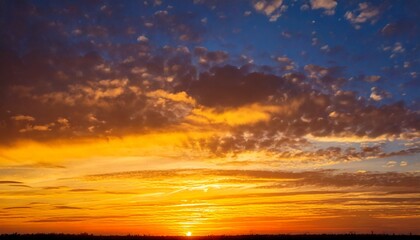 Obraz premium Golden sun dips below the horizon, painting the sky with vibrant orange and blue hues during a breathtaking sunset over the tranquil landscape.