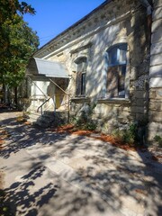 Old historic building exterior wall with windows, aged architecture facade detail, vintage stone structure, sunlight and shadows composition, urban heritage construction background