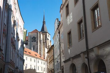 Traditional buildings lining a narrow street, with a church tower rising above them in Prague, Czech Republic