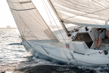 White sailboat heeling in the ocean breeze with crew onboard