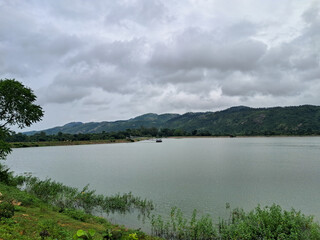 Lush Green Hillside Landscape Reflected on Calm Reservoir Water. Beautiful view of Purulia with its beautiful mountains on a rainy day.
