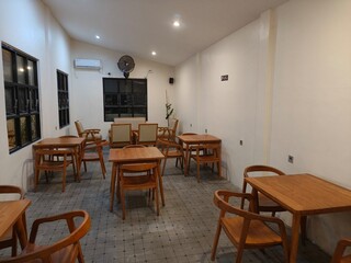 Minimalist café interior with wooden tables and chairs under warm lighting, creating a cozy and modern atmosphere. Perfect for design inspiration, restaurant marketing, or property promotion.