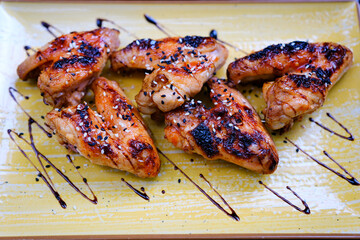 Baked chicken wings served with different sauces and lemon. Black background. High quality photo