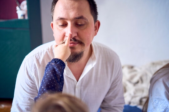 a family plays by painting each other's faces with gold glitter during a Christmas party at home