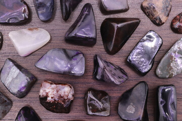 Sugilite rare jewel stones texture on black background. Sparse mineral pebbles background.