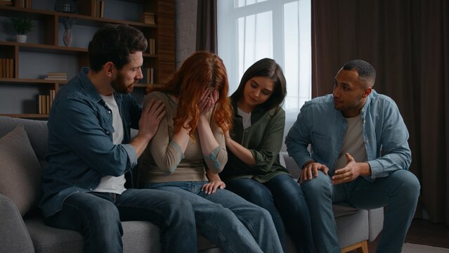 Depressed woman talking crying feeling trouble worry four friends support multiracial people men women together supporting group psychological therapy at home party diverse buddies communicate advice