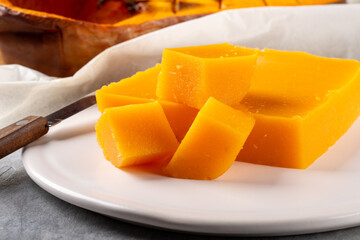 Pumpkin marmalade. Homemade pumpkin jelly candies on white plate on gray background.